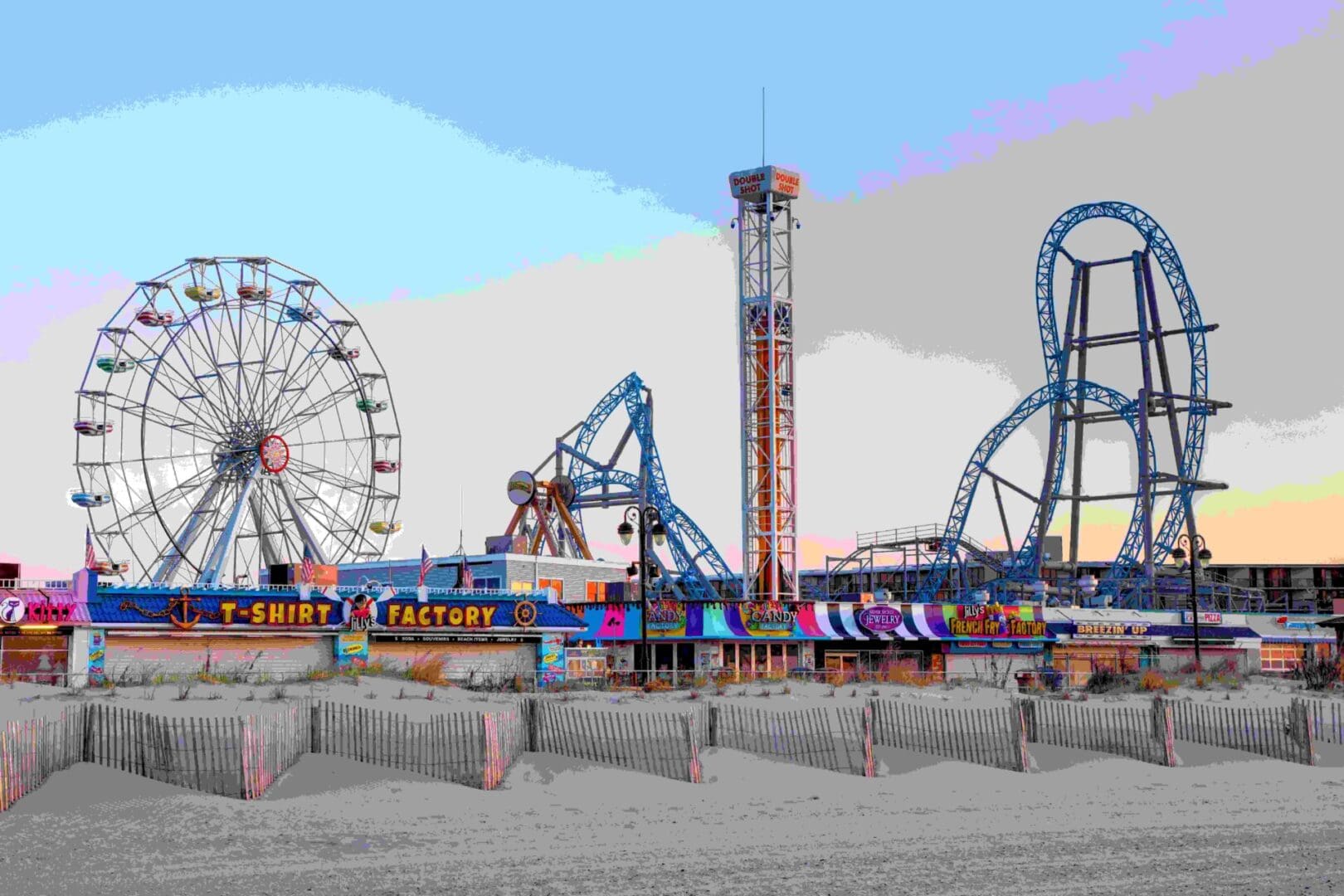 Amusement park with a large Ferris wheel, roller coasters, and various colorful rides against a clear sky. A "T-Shirt Factory" sign is visible in the foreground.